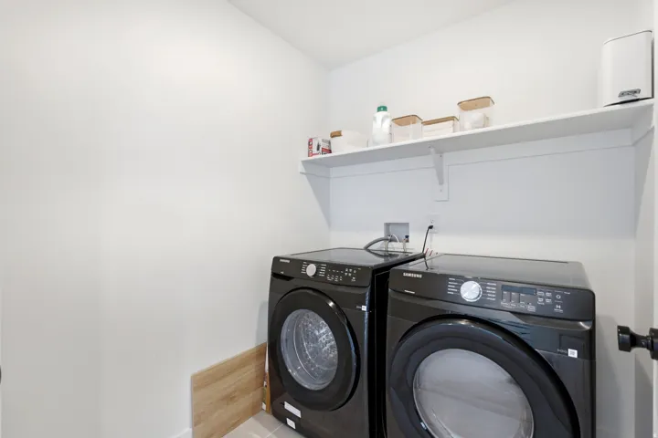 Dedicated utility area featuring white walls, a single floating shelf, and wood-finish flooring