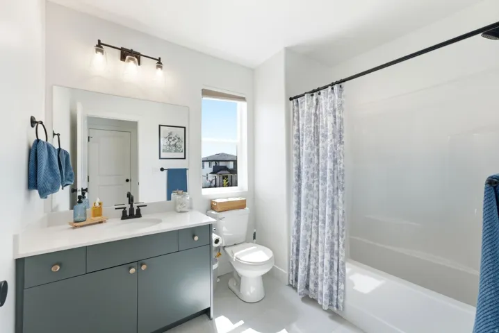 Bathroom featuring a full vanity with dark cabinetry, white countertop, and single basin sink with a matte black faucet