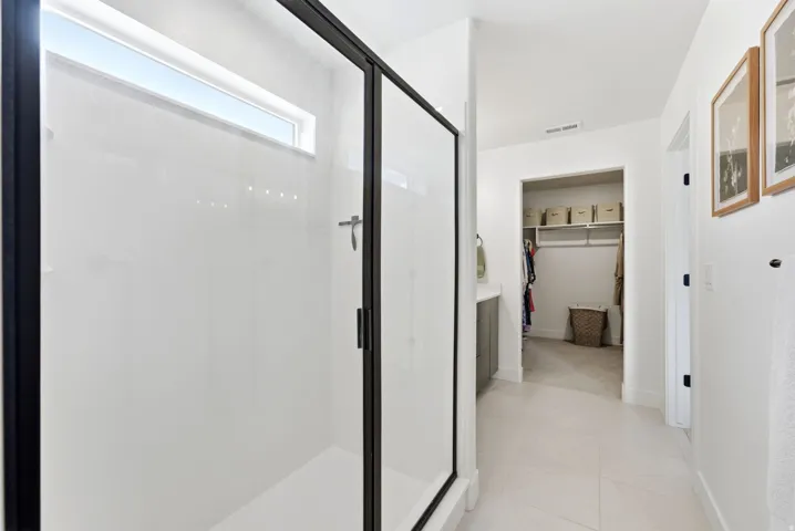 Shower enclosure with black framing, transom window, and a white shower base