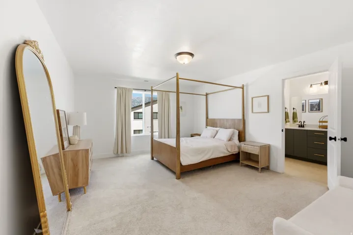 Bright bedroom featuring plush carpet flooring, a window with exterior views, and a ceiling-mounted light fixture