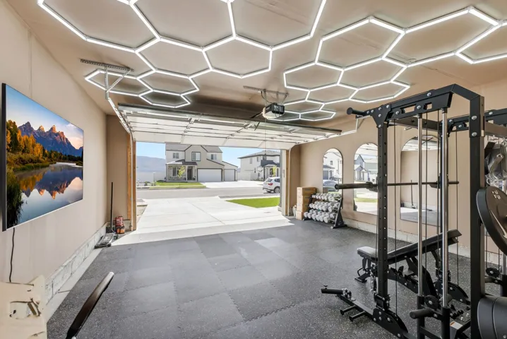 Garage interior featuring hexagonal ceiling lighting, tiled rubber flooring, and an arched mirror installation