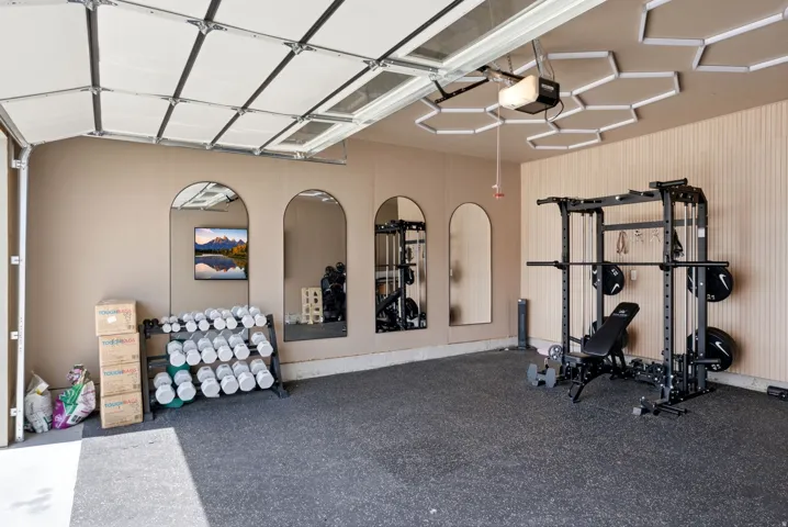 Dedicated fitness space featuring rubberized flooring and paneled accent wall