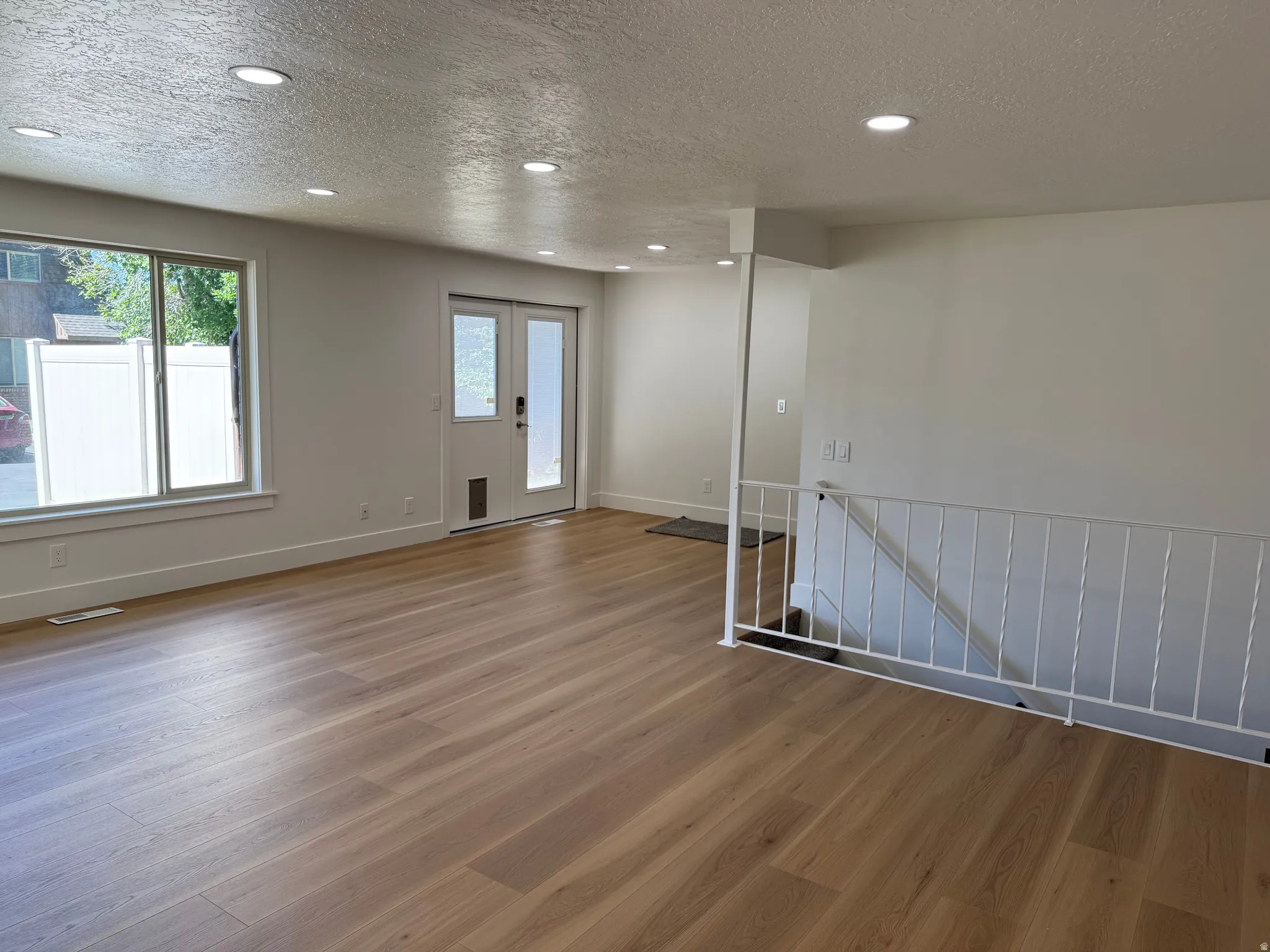 Spacious room featuring wood-finish flooring, recessed lighting, and white baseboards