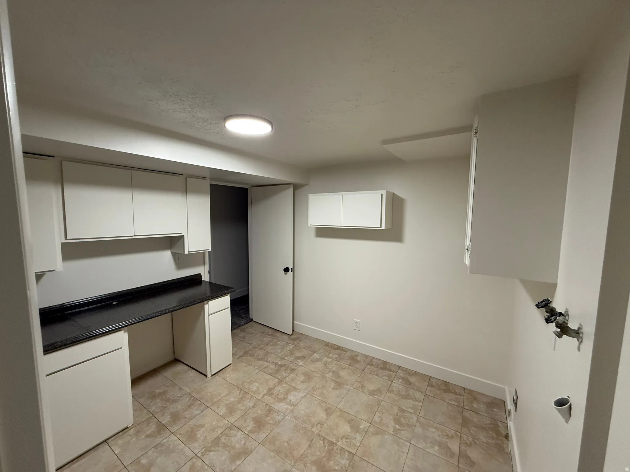 Utility room featuring tile flooring, white cabinetry, a dark speckled countertop, and laundry hookups