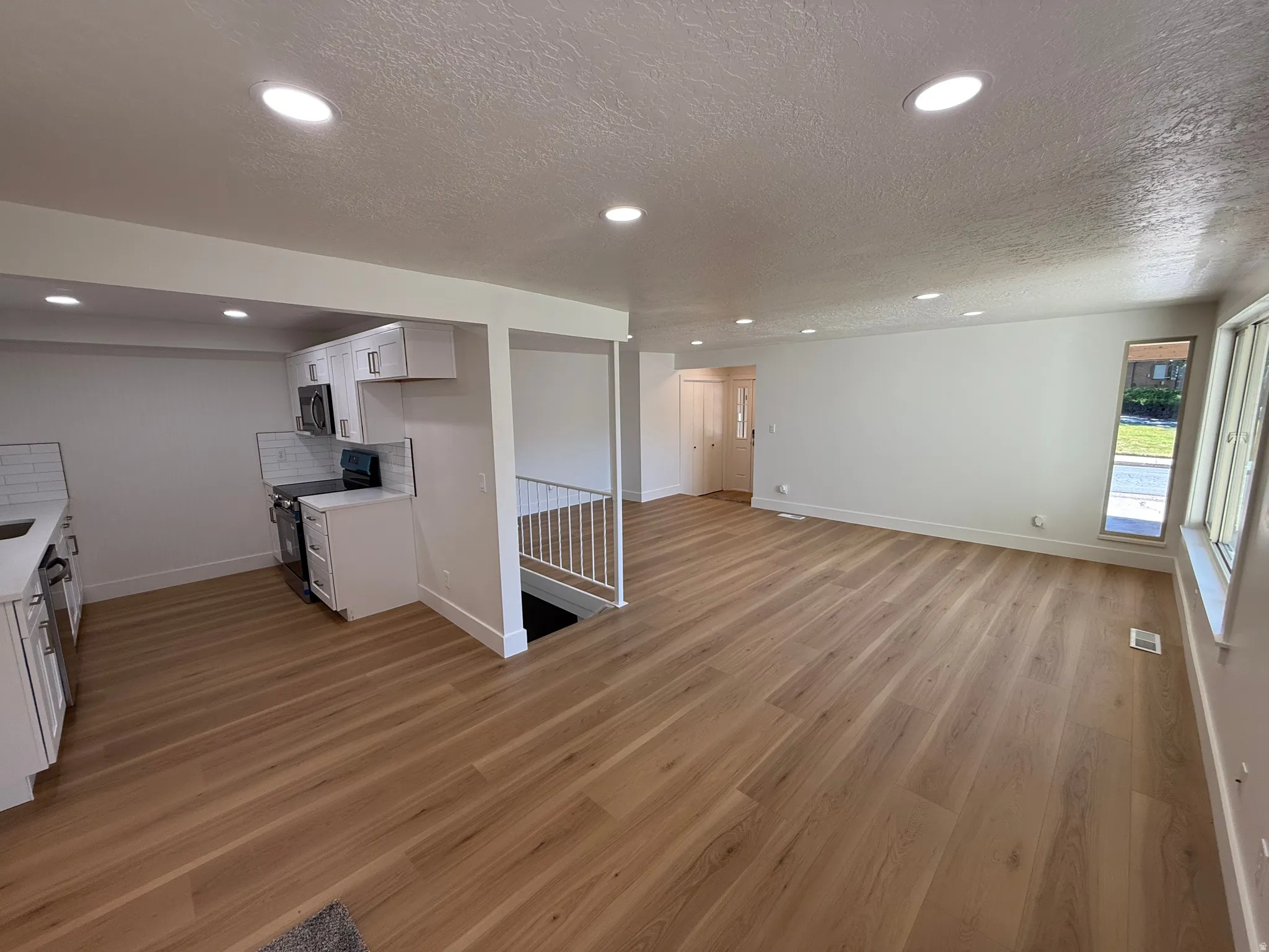 Open-concept living space featuring wood-finish flooring, recessed lighting, and white walls