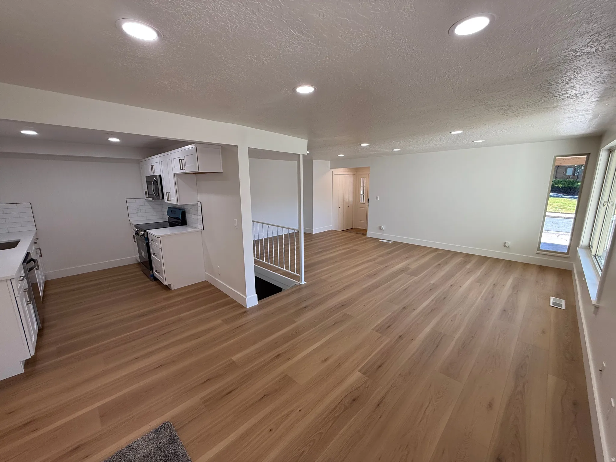 Open-concept living space featuring wood-finish flooring, recessed lighting, and white walls