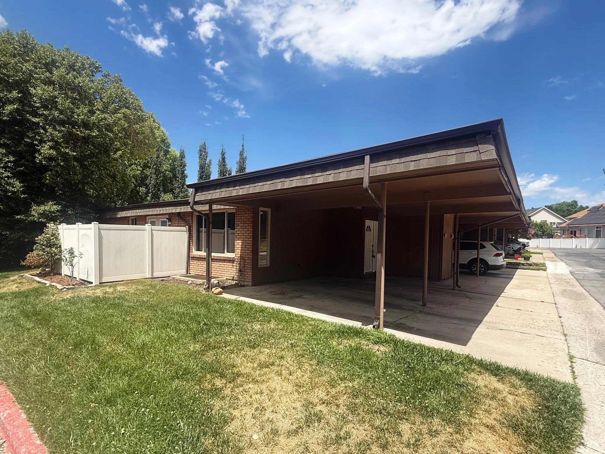 Multi-unit property featuring brick and brown siding with multiple covered carport spaces