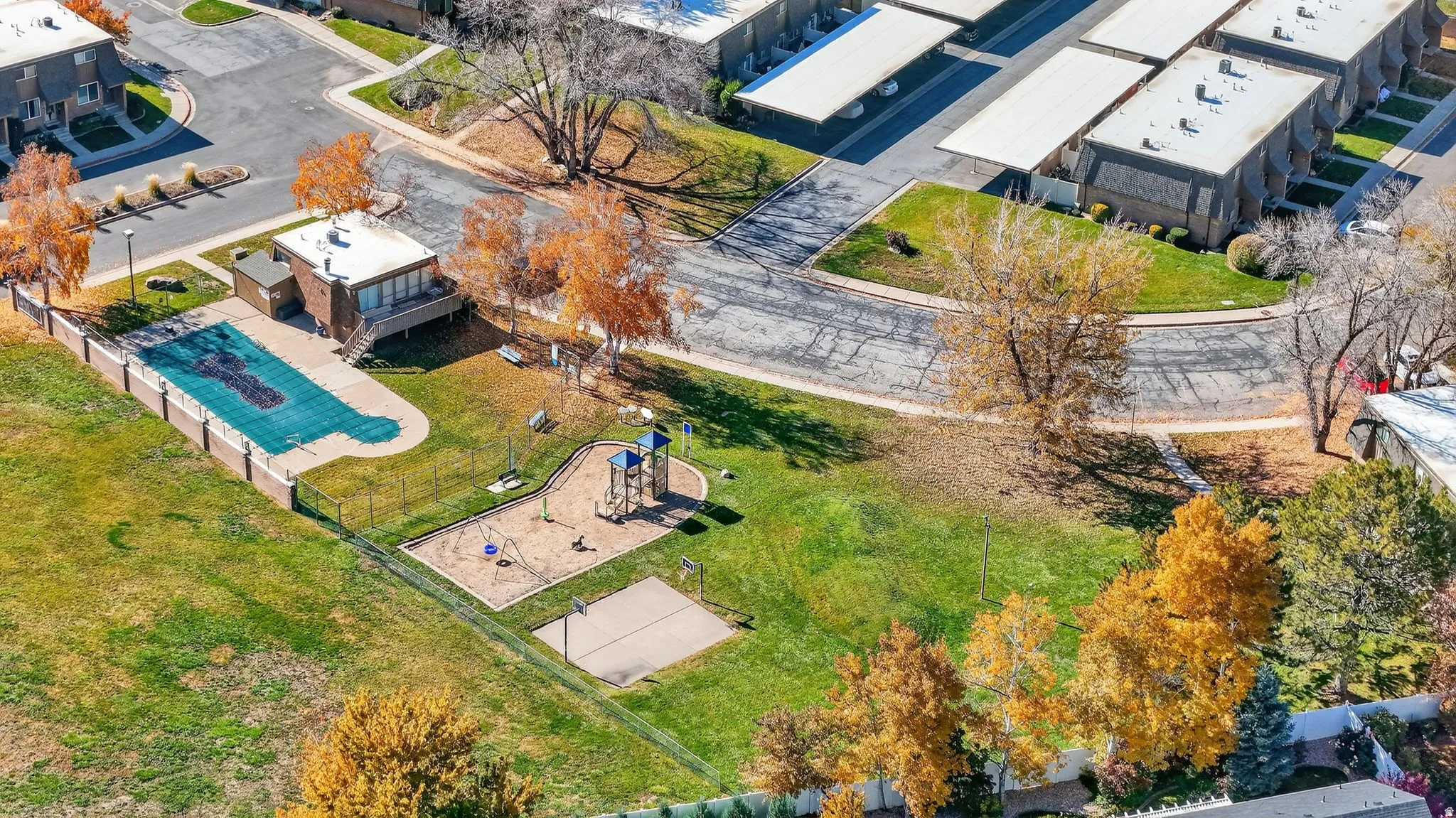 Community amenities featuring a fenced pool area, adjacent clubhouse, and a playground with a sandbox area