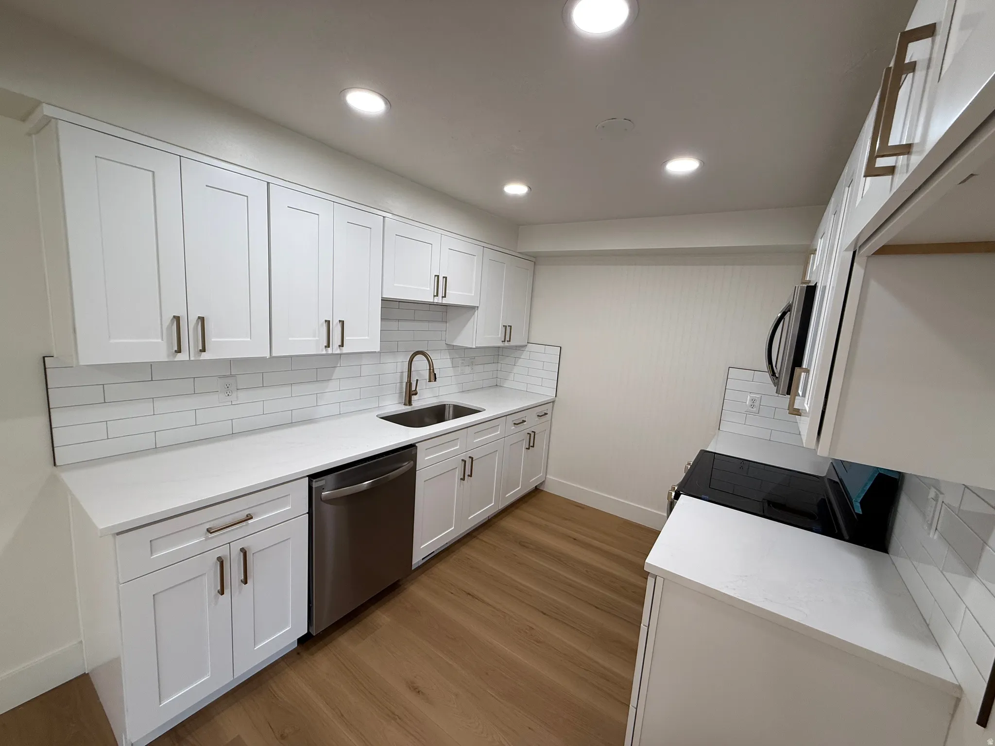 Modern kitchen featuring white shaker cabinetry and quartz countertops