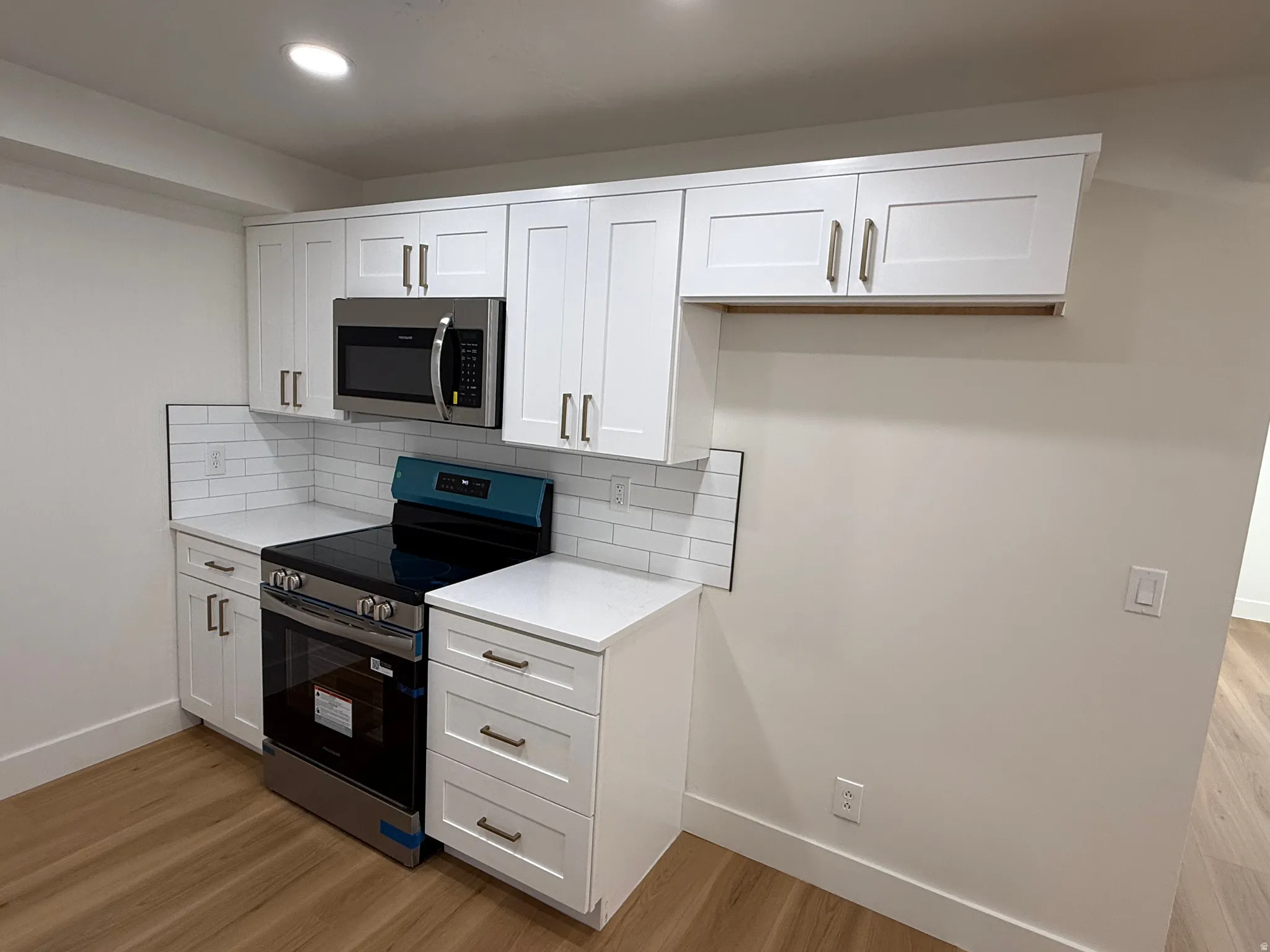 Kitchen area featuring white shaker-style cabinetry, a stainless steel range, and an over-the-range microwave