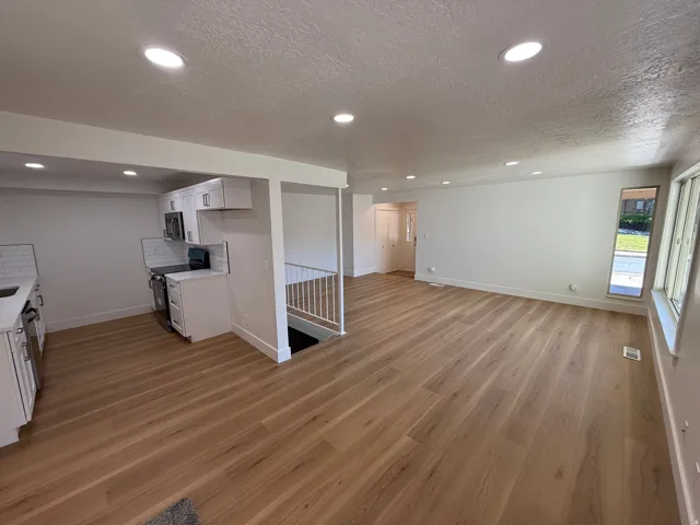 Open-concept living space featuring wood-finish flooring, recessed lighting, and white walls