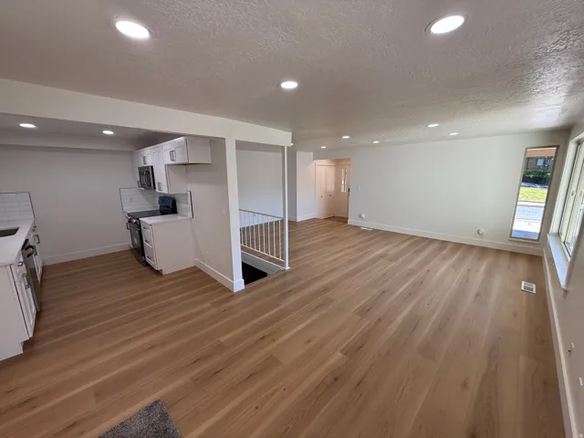 Open-concept living space featuring wood-finish flooring, recessed lighting, and white walls
