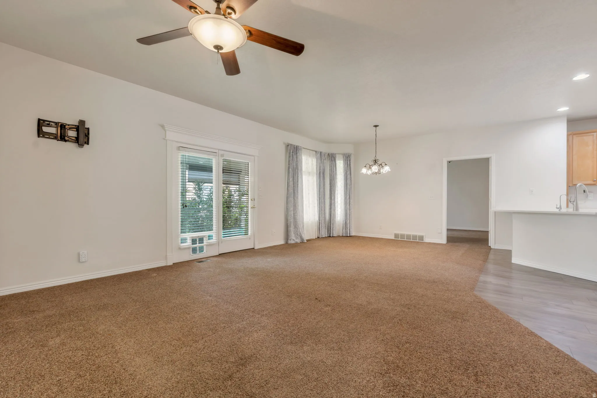 Spacious living area featuring neutral carpet and abundant natural light from extra end unit windows, patio doors