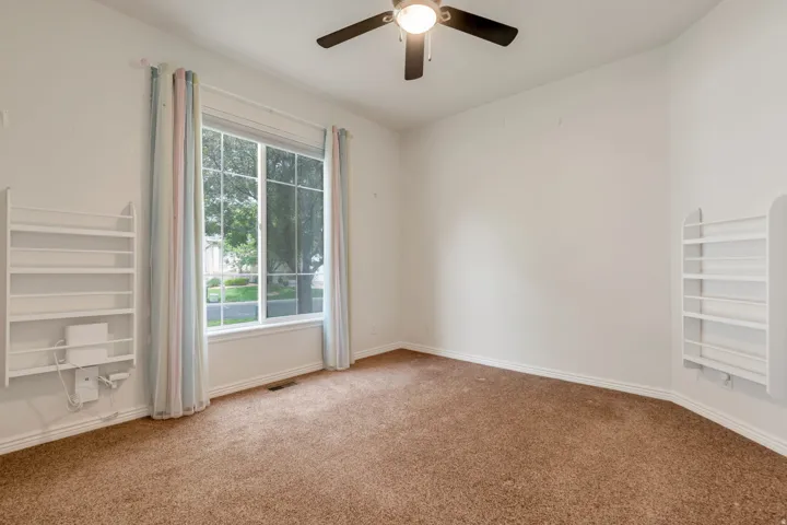guest bedroom with large end unit window, ceiling fan and large closet with organizer