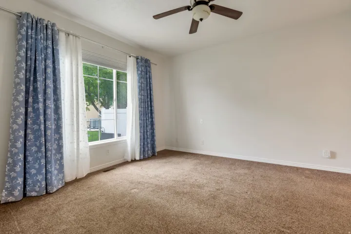 Primary bedroom with large window and ceiling fan