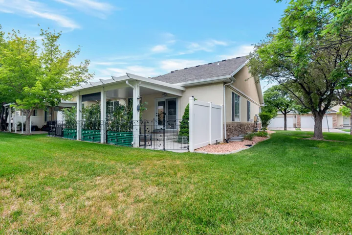 Rear exterior featuring a covered patio with white pergola, stucco siding, and stone accents