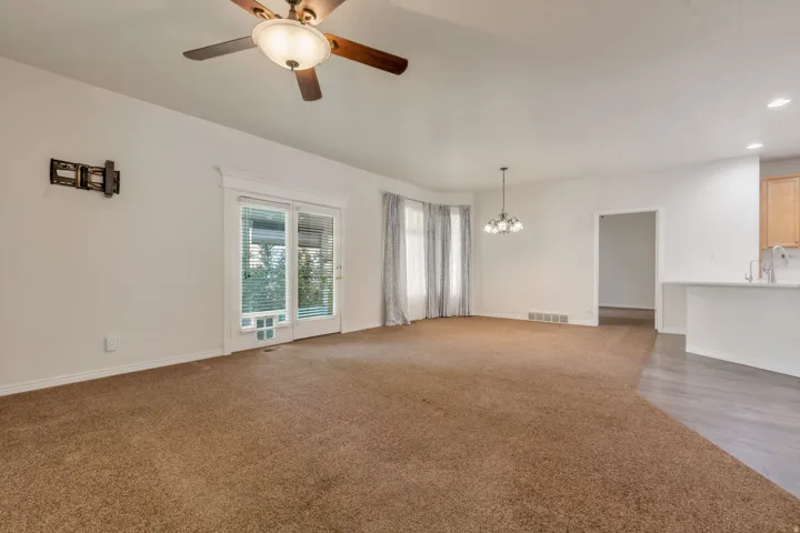 Spacious living area featuring neutral carpet and abundant natural light from extra end unit windows, patio doors