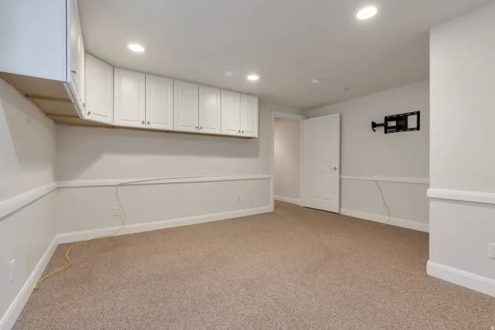 Recessed lighting illuminates this carpeted room featuring extensive white upper cabinetry, white baseboards, and white chair rail molding  OR BEDROOM  extensive storage in this area