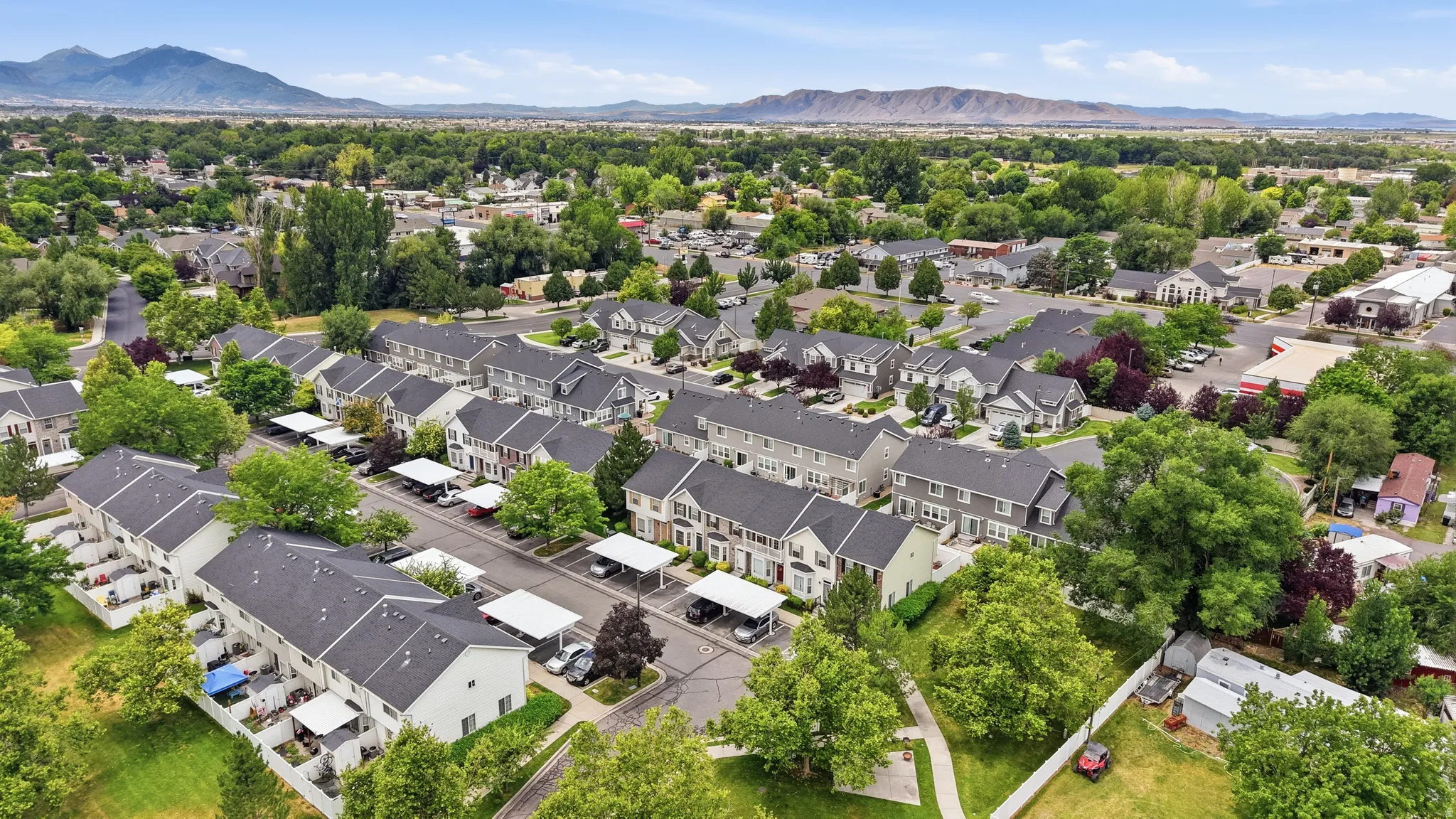 Aerial perspective showcasing a residential community with uniform townhomes featuring dark shingle roofs and light-colored siding