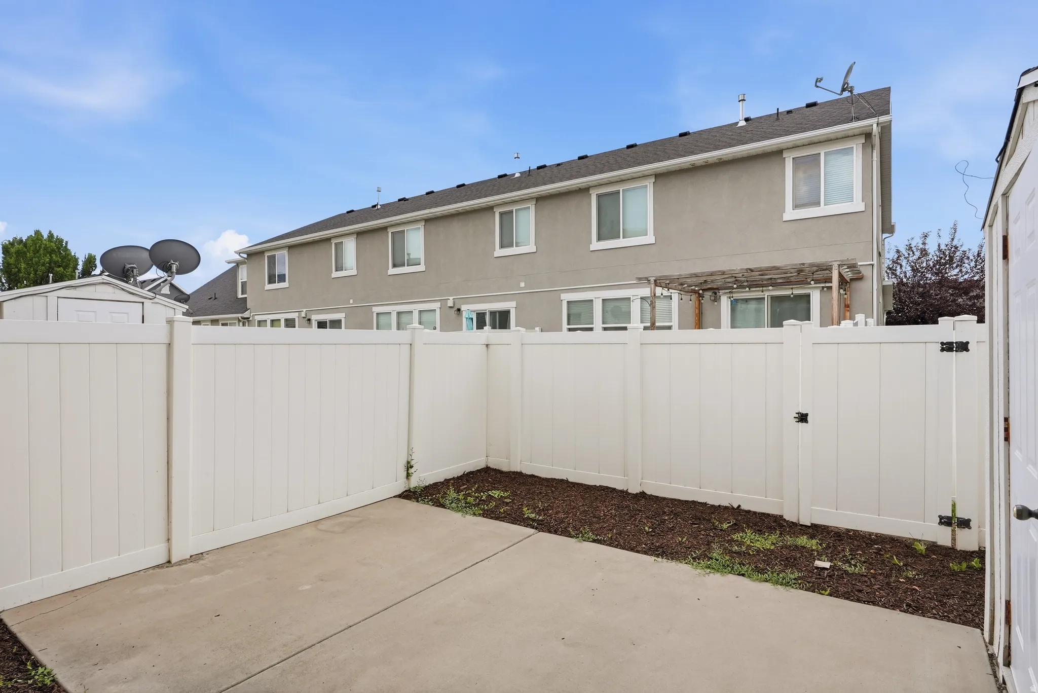 Private backyard featuring a concrete patio, vinyl fencing, and a pergola structure