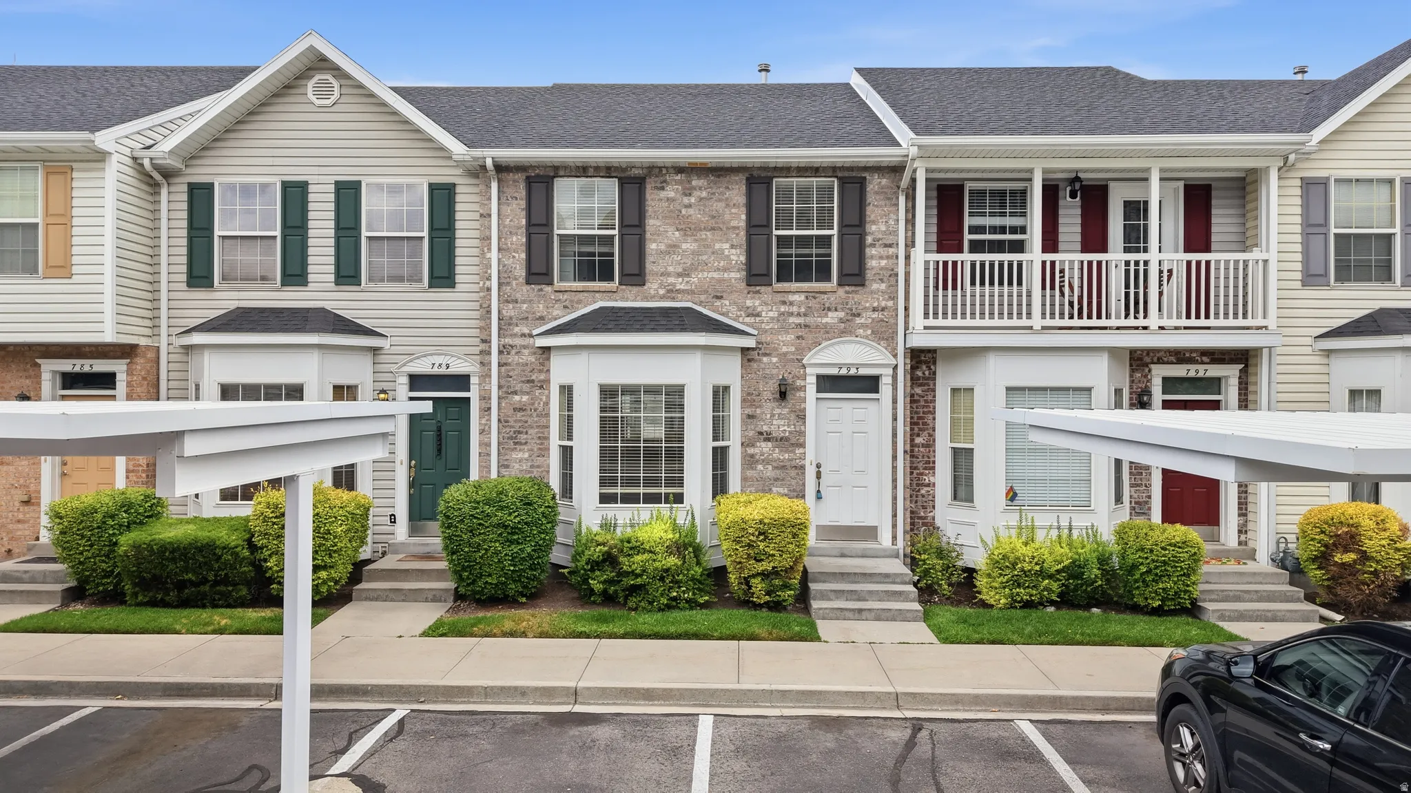 Townhome exterior featuring a bay window, brick and siding facade, covered entry, and dedicated carport parking