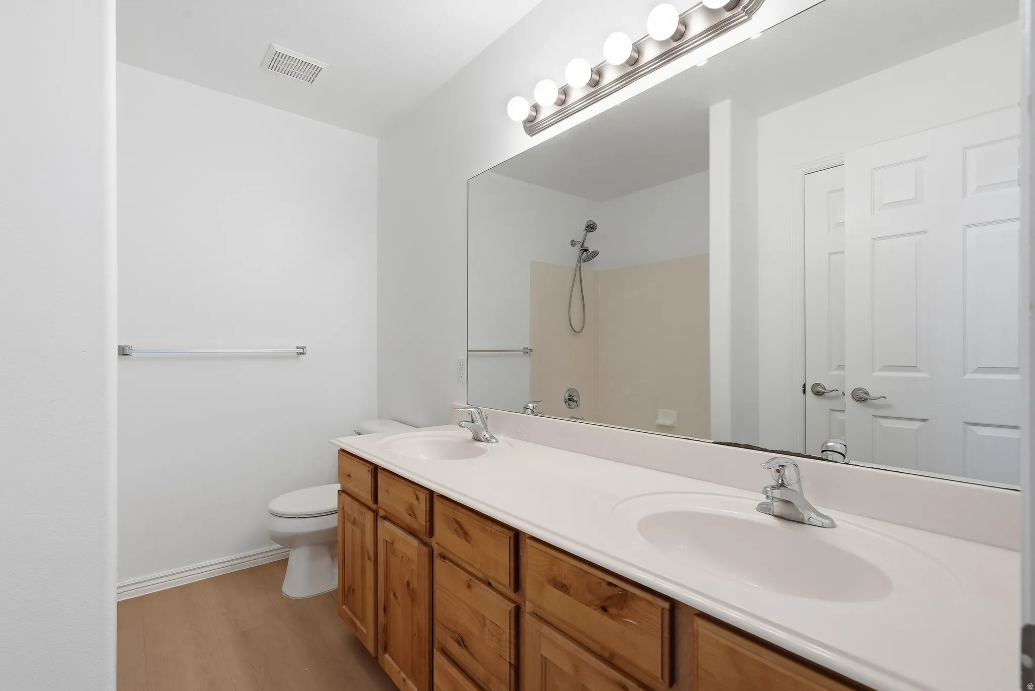 Dual vanity with light wood-finish cabinetry and integrated sinks