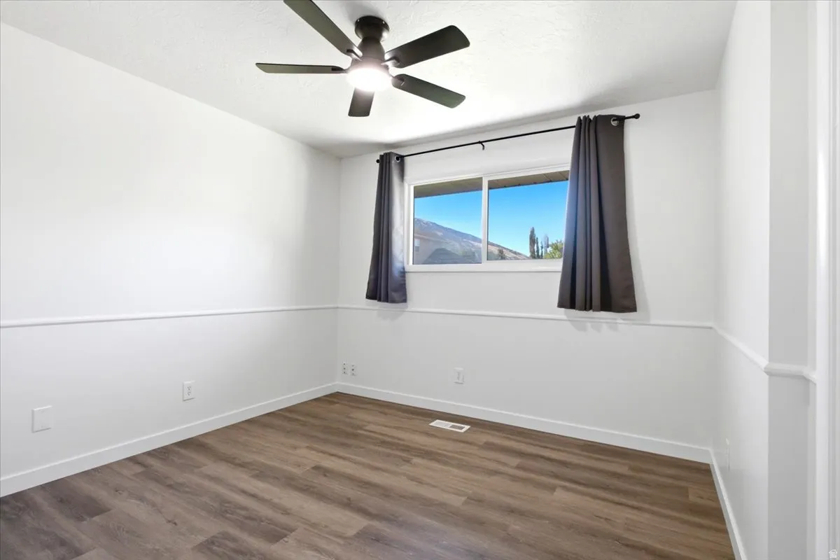 Neutral white walls with chair rail molding and wood-finish flooring