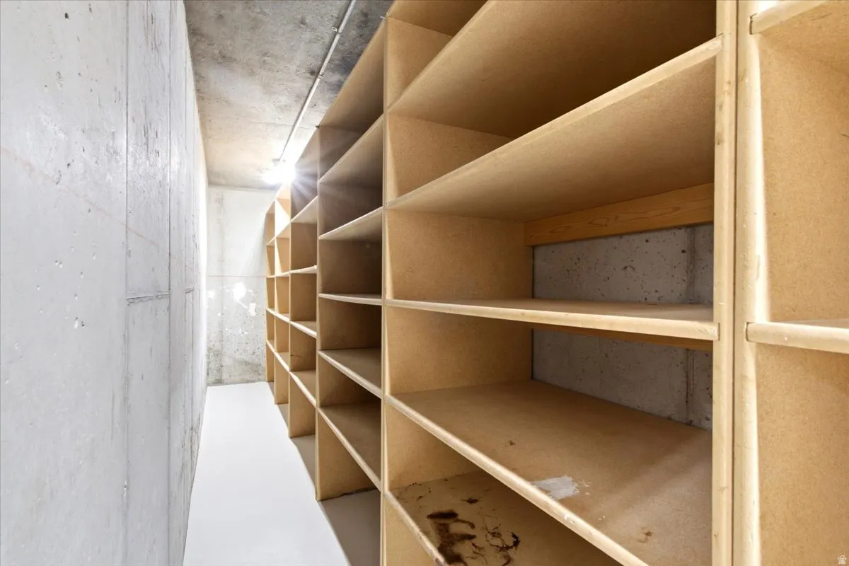 Built-in shelving system with multiple compartments, concrete walls, concrete ceiling, and light-toned flooring