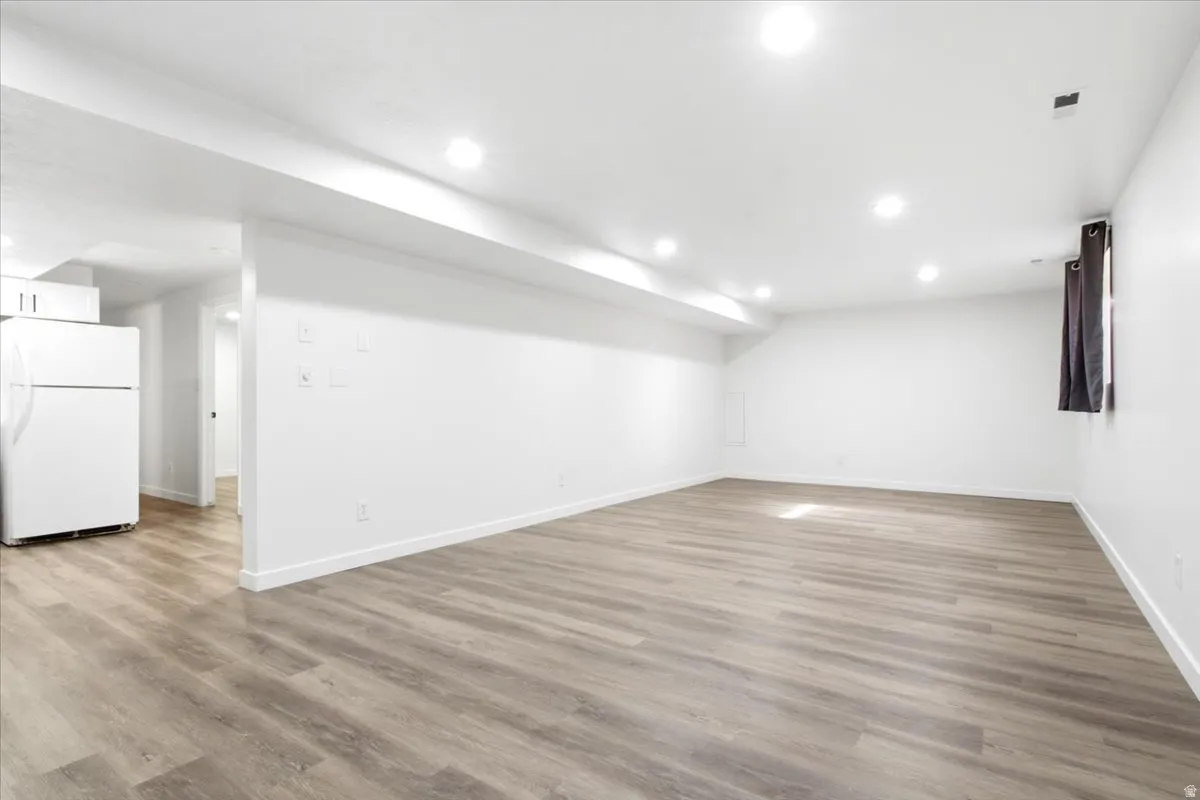 Spacious interior with wood-finish flooring, recessed lighting, white walls, and white trim
