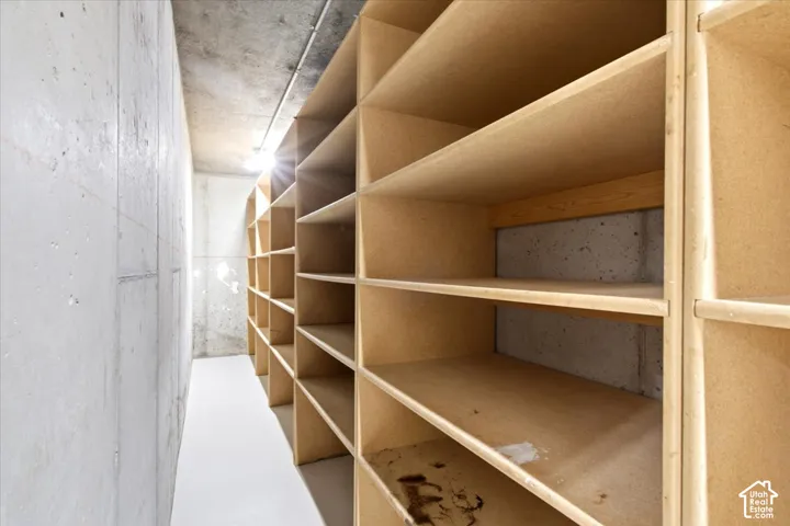 Built-in shelving system with multiple compartments, concrete walls, concrete ceiling, and light-toned flooring