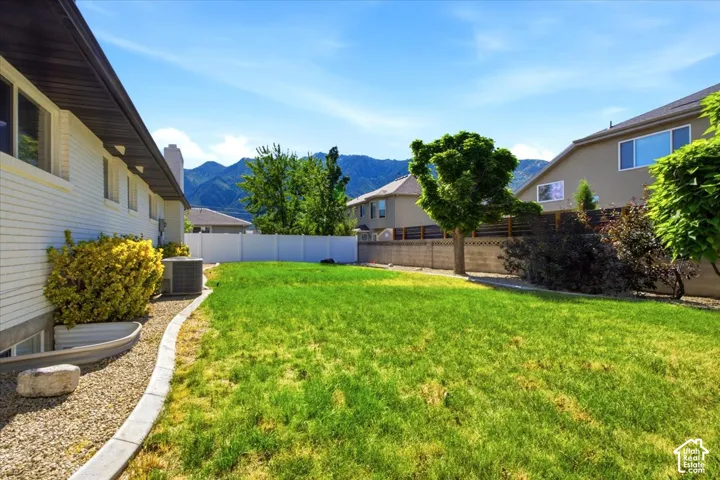 Expansive backyard featuring a lush lawn, a white privacy fence, and mature trees with great mountain views.