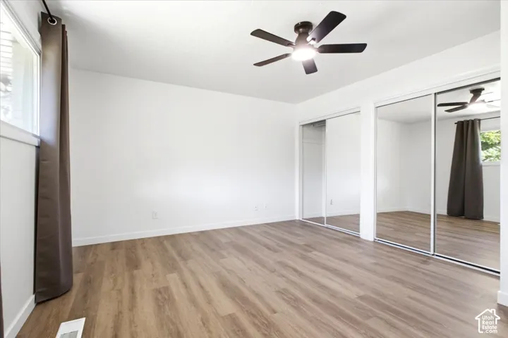 Master bedroom featuring wood-finish flooring, a contemporary ceiling fan, and large mirrored closet doors