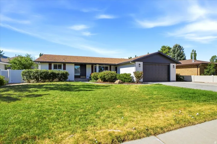 Ranch-style residence featuring a brown shingle roof, white painted brick, and dark shutters