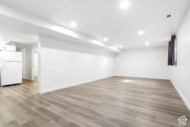 Spacious interior with wood-finish flooring, recessed lighting, white walls, and white trim