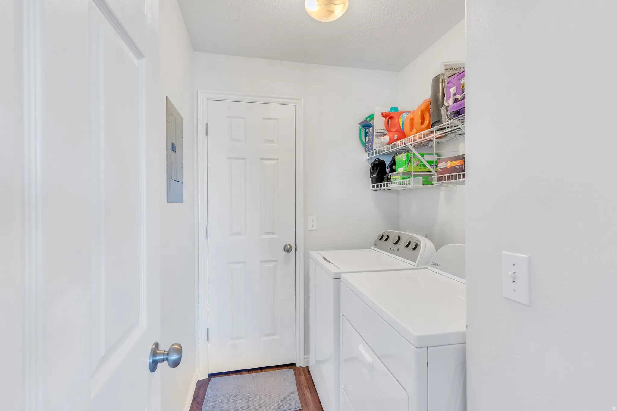 Dedicated laundry area featuring white washer and dryer, wire shelving, wood-finish flooring, and a flush-mount ceiling light