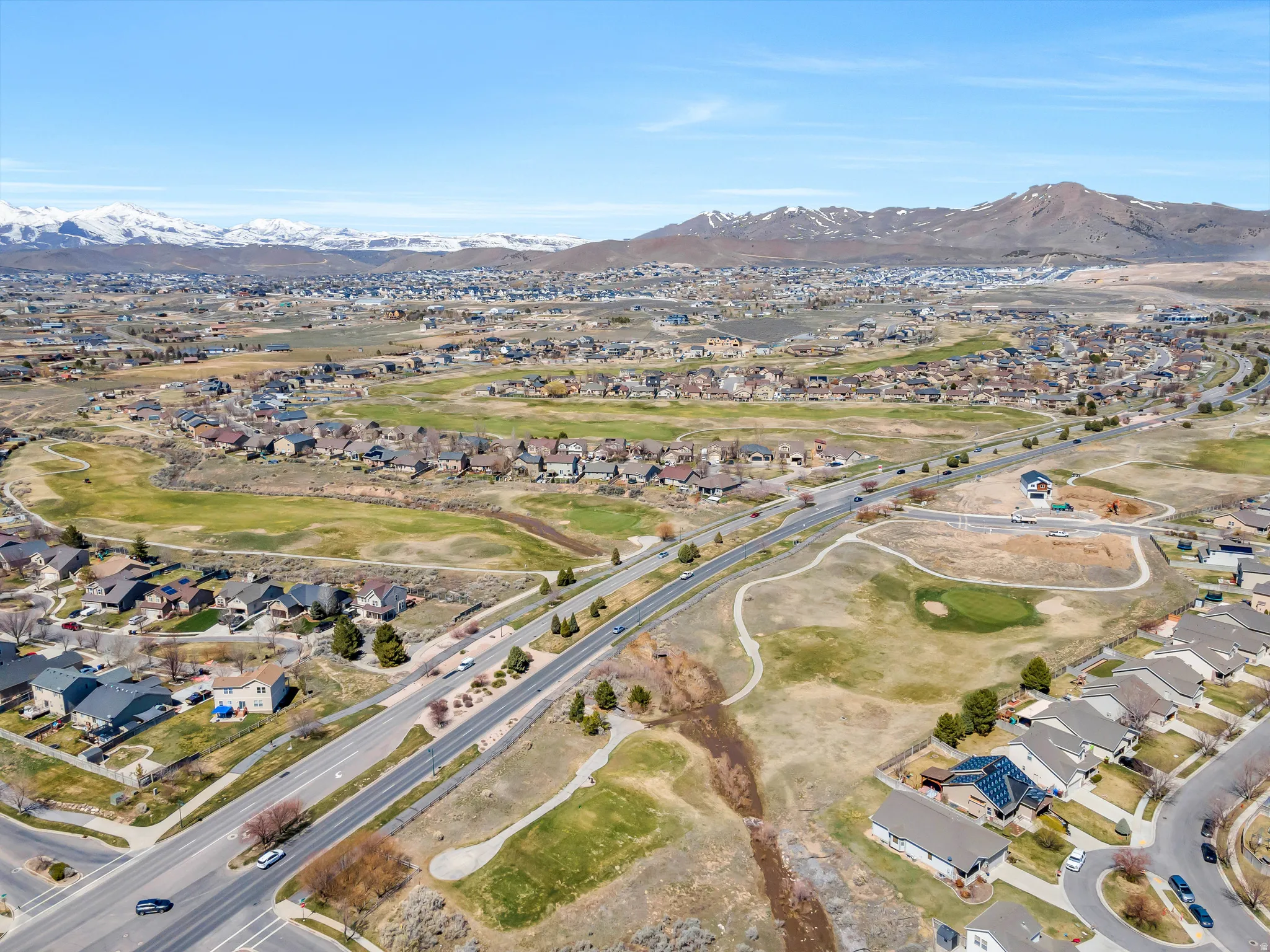 Expansive residential area featuring numerous homes set amidst open green spaces and roads