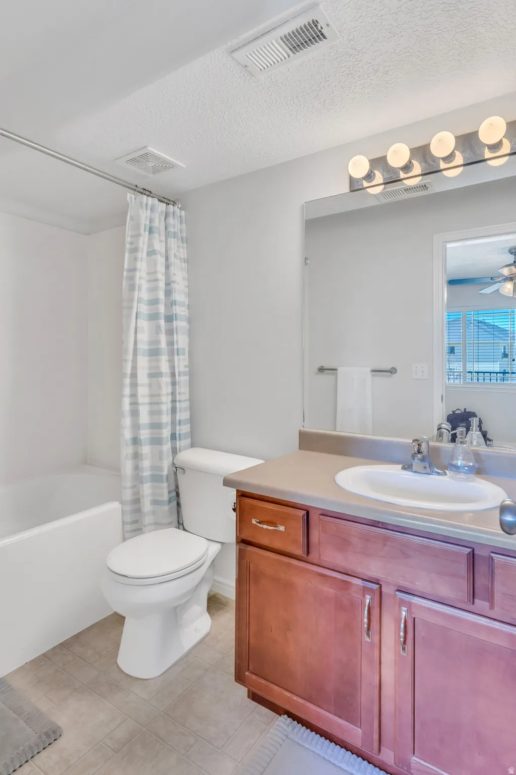 Bathroom featuring a wood-finish vanity with an integrated sink, a full-width mirror, and a contemporary five-bulb vanity light fixture