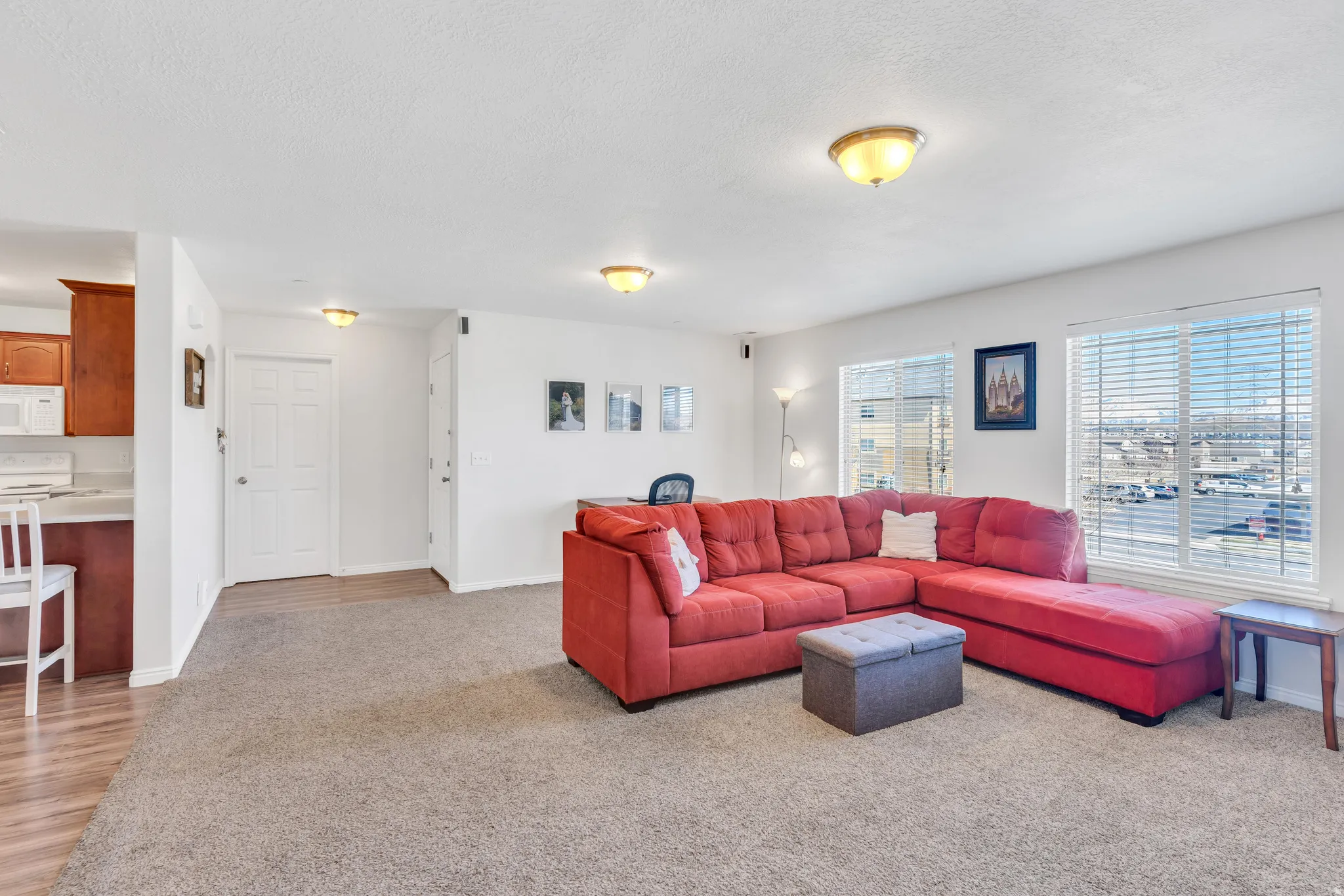 Open-concept living area featuring neutral carpet flooring and white walls