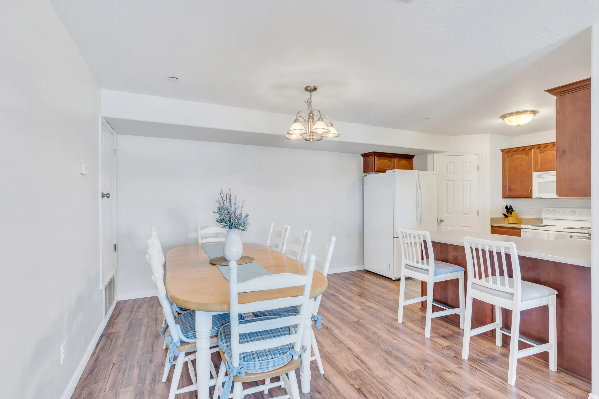 Open-concept dining area featuring wood-finish flooring, a contemporary chandelier, and recessed lighting
