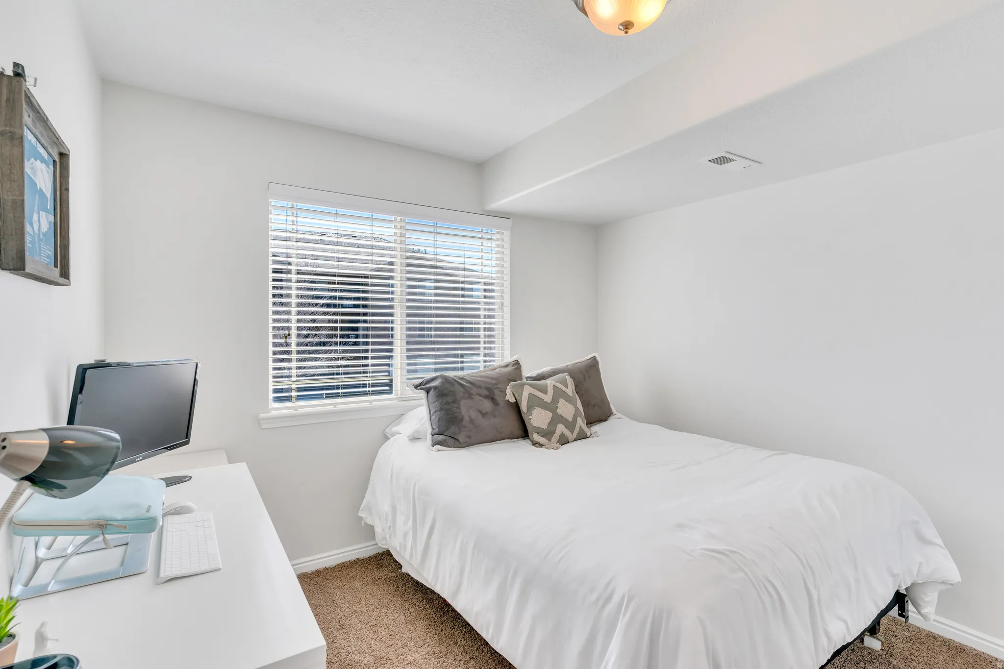 Bright room featuring a window with horizontal blinds, neutral wall paint, and brown carpet flooring