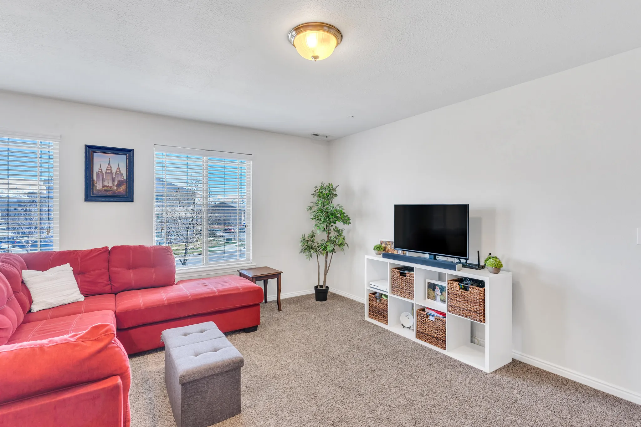 Carpeted living area featuring multiple windows with blinds, providing natural illumination