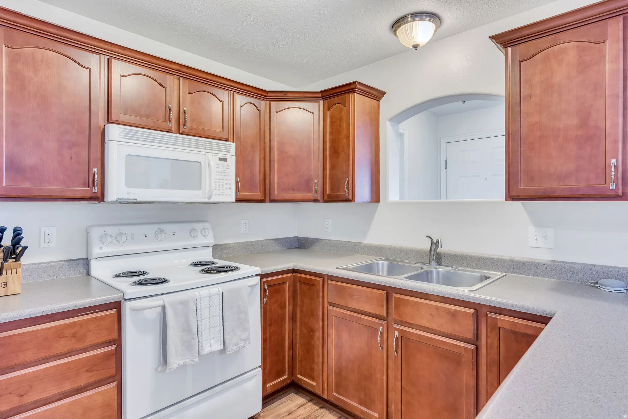 Kitchen featuring wood-finish cabinetry, solid surface countertops, a white electric range, and an over-the-range microwave