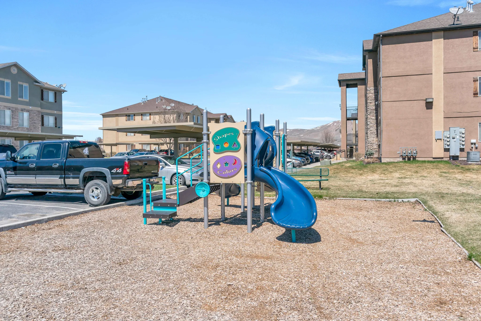 Community playground featuring a slide and climbing elements, set on a wood chip base