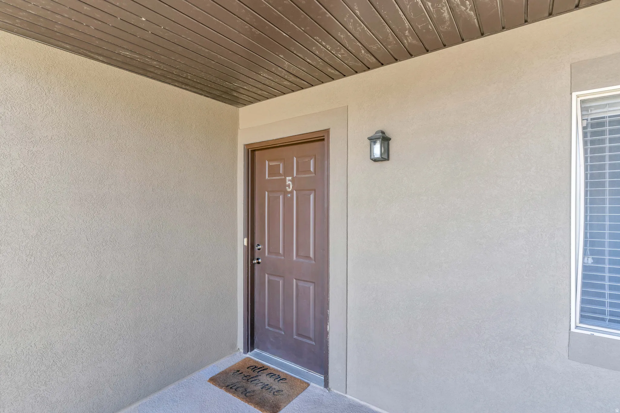 Textured stucco exterior with a brown paneled entry door