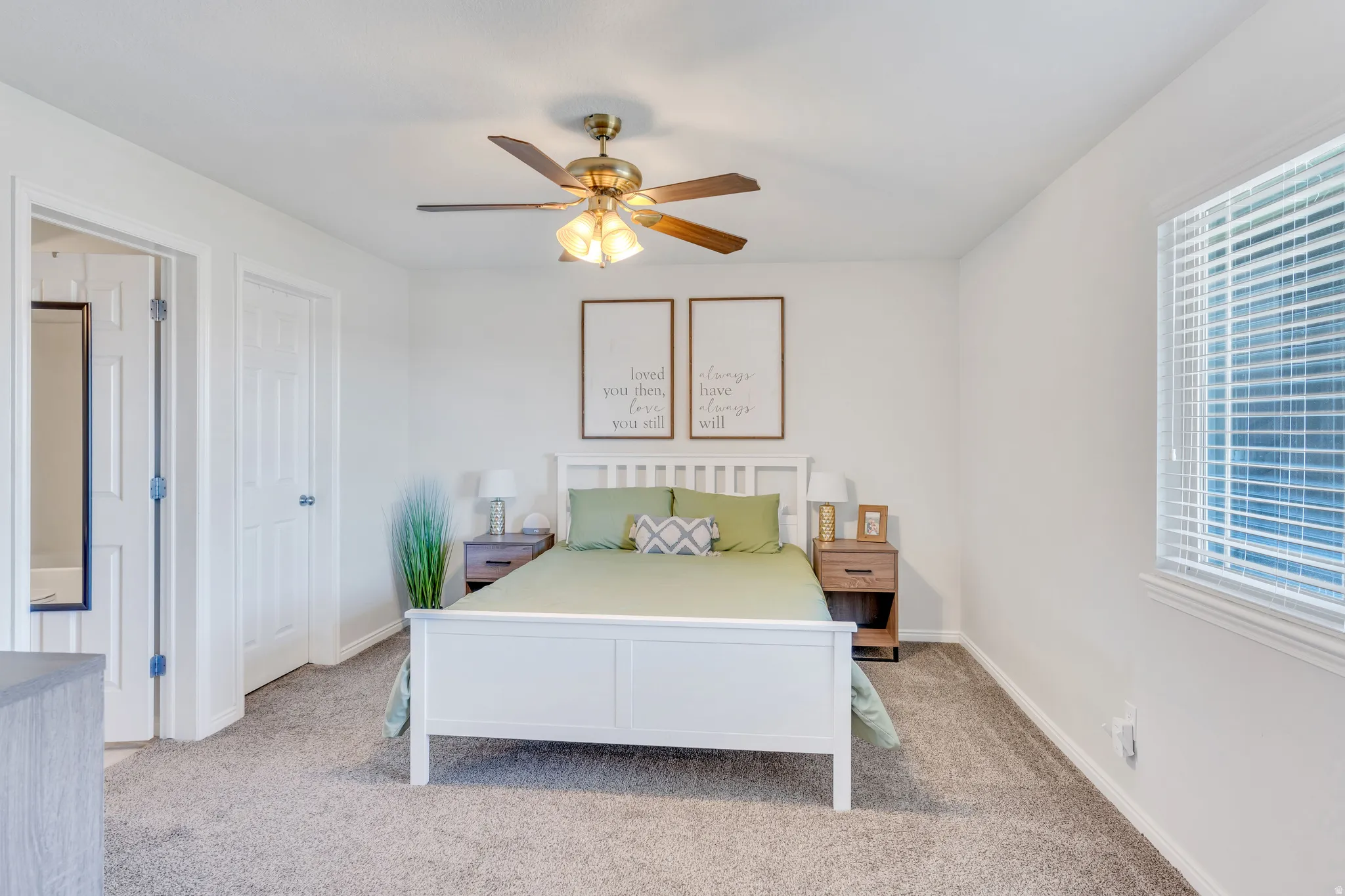 Carpeted interior space featuring a ceiling fan with integrated lighting, a window with horizontal blinds, and a white six-panel door