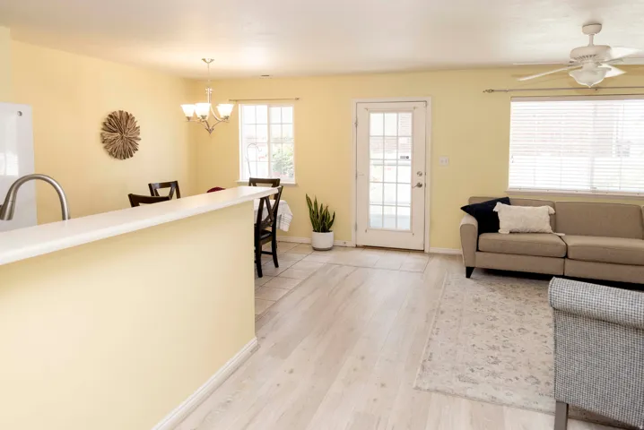 Open-concept living area featuring wood-finish flooring, a ceiling fan, and a glass-paneled door