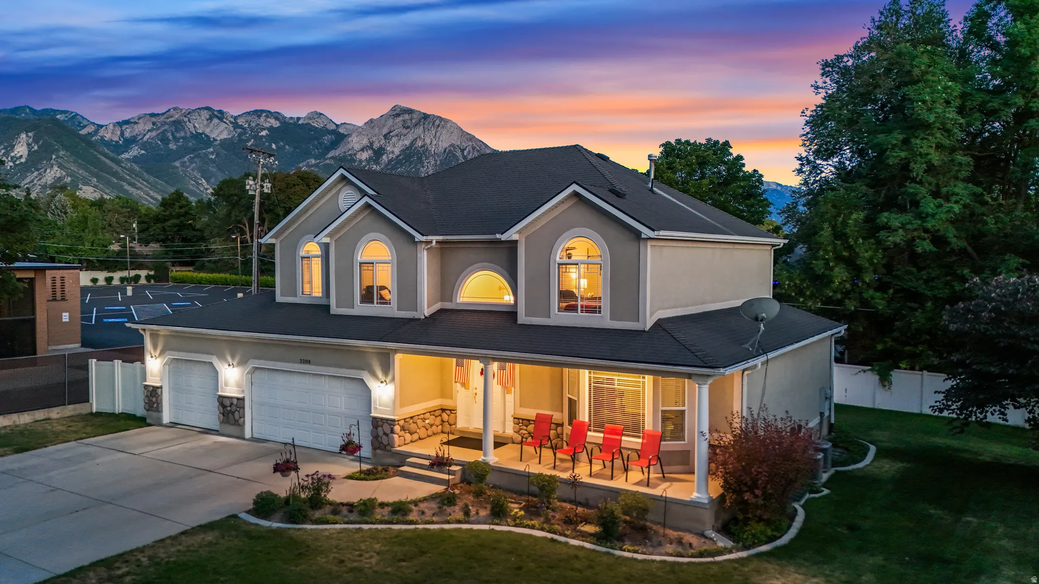 Two-story stucco property featuring a dark shingle roof and prominent arched windows