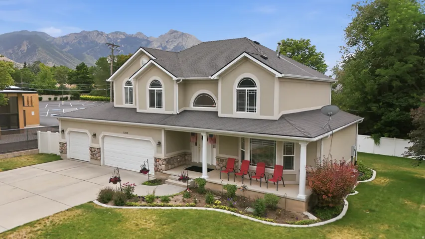 Two-story residence featuring stucco and stone veneer exterior, an attached three-car garage, a covered front porch with white columns, and arched windows