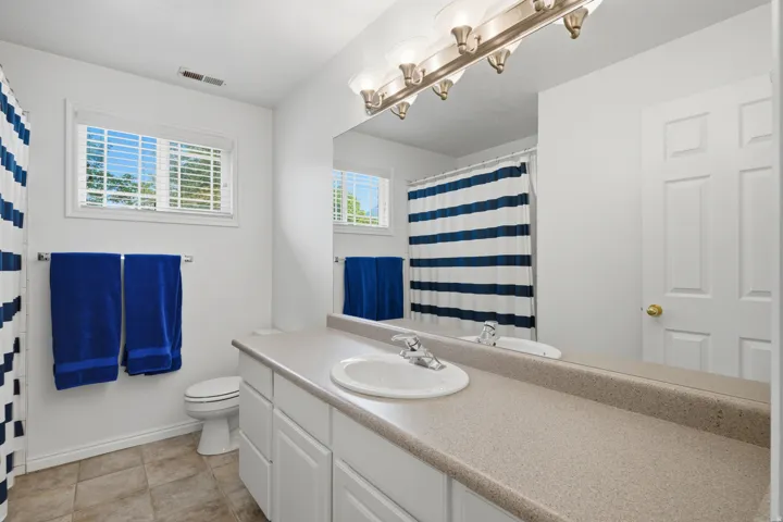 Bathroom featuring a single vanity with an integrated sink, expansive mirror, and tile flooring