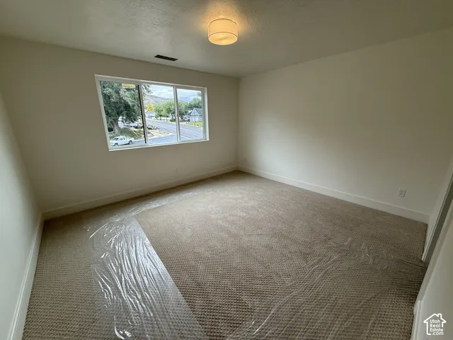 Neutral wall tones, wall-to-wall carpeting, large window, and drum-style flush-mount lighting